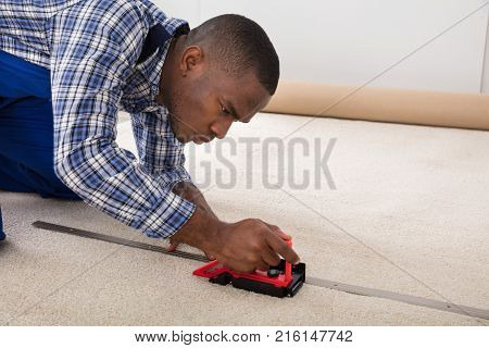 Young Craftsman Installing Carpet On Floor Using Fitter