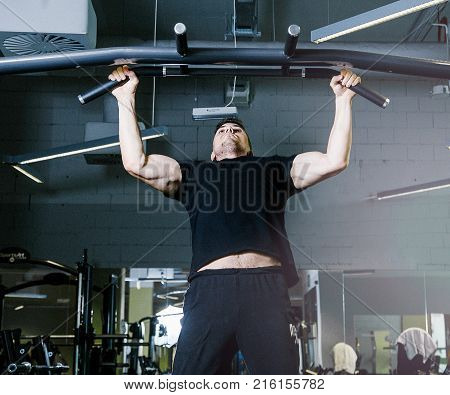 Tightening on the crossbar. Sports exercises with a crossbar.   Work of personal trainer. Portrait Of Personal Trainer In Sports Outfit In Fitness Center Gym Standing Strong.