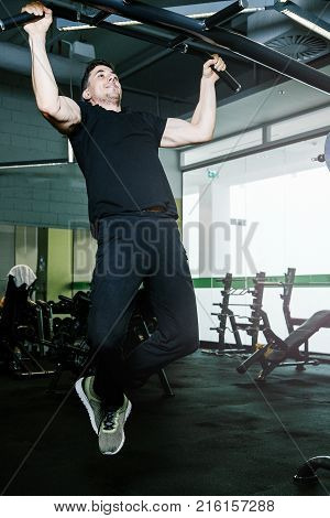 Tightening on the crossbar. Sports exercises with a crossbar.   Work of personal trainer. Portrait Of Personal Trainer In Sports Outfit In Fitness Center Gym Standing Strong.
