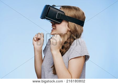 Young beautiful woman on a light blue background with virtual reality glasses.