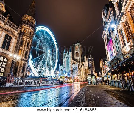 Ghent, Belgium - January 3th, 2017. Gent city winter festival in Flanders. Christmas fair with ferris wheel, illumination and Xmas decorations near Saint Nicholas Church on the Ghent Old town square.