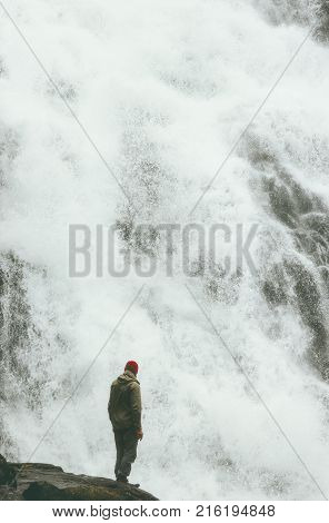 Wayfarer Man standing alone on cliff at big waterfall outdoor Travel Lifestyle success concept adventure vacations wild nature