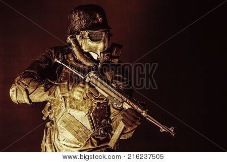 Futuristic nazi soldier gas mask and steel helmet with schmeisser handgun black background studio shot
