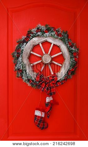 Christmas wreath, cones and evergreen boughs on a red door.