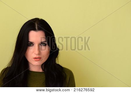 Portrait young beautiful women. The woman has green eyes and black hair. The woman is dressed in a green jacket.