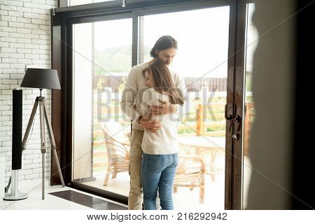 Young man and woman hugging standing at home interior, tender husband embracing wife gently, showing love and support, couple reconciliation concept, understanding in relationships, making up