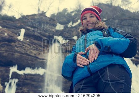 Active young pregnant woman forming a heart on her belly. Motherly love.