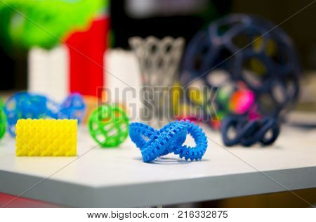 Many abstract models bright colorful objects printed on a 3d printer on a white table. Fused deposition modeling, FDM. Progressive modern additive technology. Concept of 4.0 industrial revolution