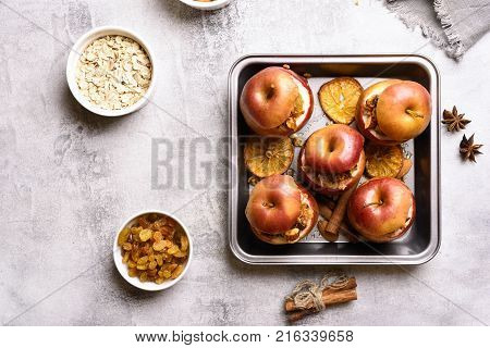 Healthy ftuit dessert. Baked apples with granola cinnamon nuts and honey on stone background. Top view flat lay