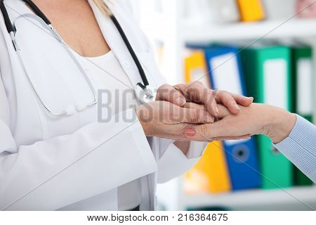Hand of doctor reassuring her female patient. Medical ethics and trust concept