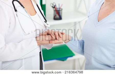 Hand of doctor reassuring her female patient. Medical ethics and trust concept