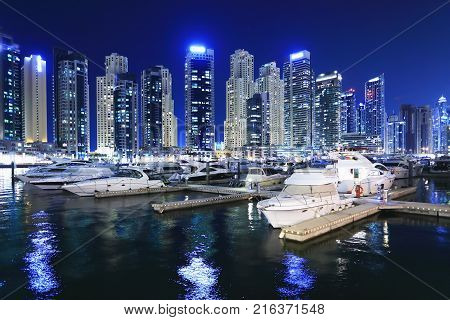 Marina with luxury yachts in Dubai at night. Night skyline of Dubai. Business district of Dubai at night.