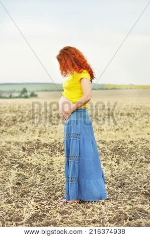 Pregnant woman. Pregnancy. 
Young pragnant woman on field