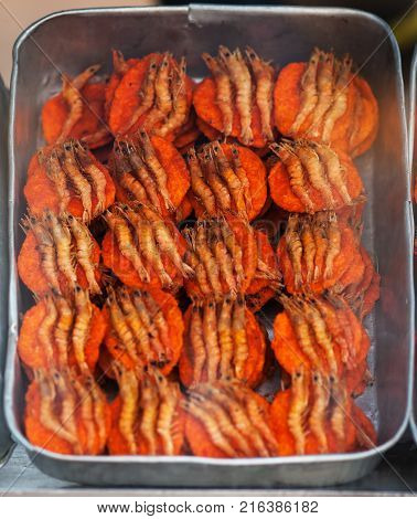 The tray with sandwiches with round orange cutlets from fish forcemeat and shrimps from above lies on a counter in street snackbar waiting for hungry buyers.