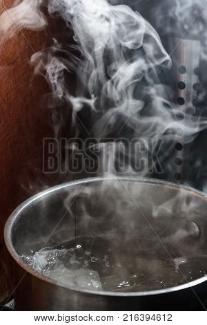 Steam rises above the boiling water in a metal pan