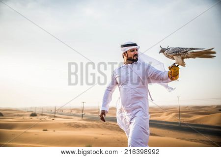 Arabian man walking in the desert at sunrise