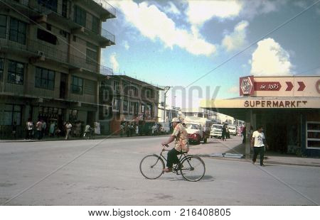 NUKU'ALOFA / TONGA - CIRCA 1990: A man rides a bicycle on Taufa'ahau Road, the principal avenue in downtown Nuku'alofa.