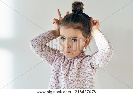a little girl with a cheerful mischievous joyful expression of the Hamming and showing tongue at the camera waving. close-up portrait in natural light