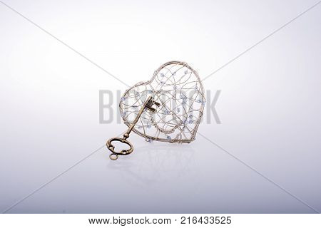 Key And A Heart Shaped Metal Cage On White