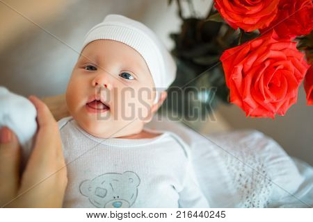 Attentive the baby is lying on his back in a bright room and looks at his mom