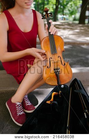 classical music instrument. woman takes violin out of a case to play in the street. art hobby earning money concept