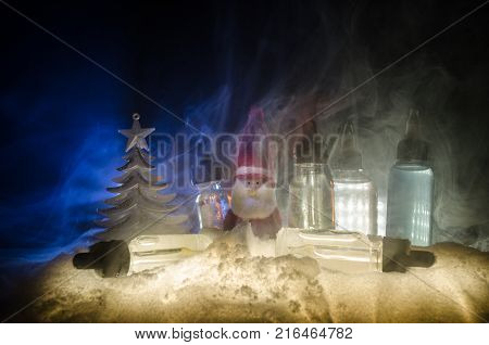 Electronic Cigarette With Vape Liquids And Christmas Decorations On Bokeh Lights Background