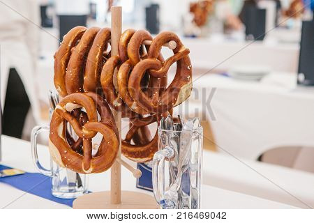 Celebration of the famous German beer festival Oktoberfest. Traditional pretzels called Brezel hang on the stand on the table. Waiting for visitors, cooked tables to celebrate the event