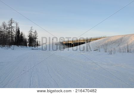Winter bridge over the frosty and snowy river