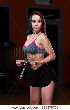 Sexy fitness woman wearing sports cloth holding the handle of fitness machine in the gym.