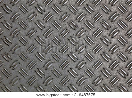 Dark gray industrial anti slip embossed metal steel plate with double diagonal bumps of diamond pattern texture, background, close up