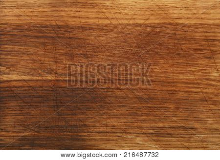 Close up texture background of brown oak wood kitchen cutting board with dark burn stains and knife cut traces