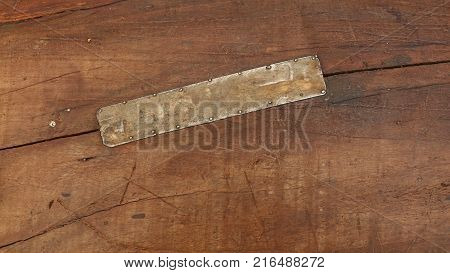 Grunge background texture of brown wood with dirty stains, scratches, cracks and nailed tin metal patch, close up