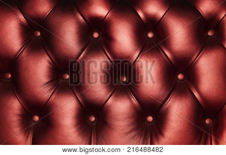 Burgundy dark red capitone genuine leather background, retro Chesterfield style soft tufted furniture upholstery with deep diamond pattern and buttons, close up