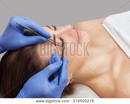 Eyelash removal procedure close up. Beautiful Woman with long lashes in a beauty salon. Eyelash extension.