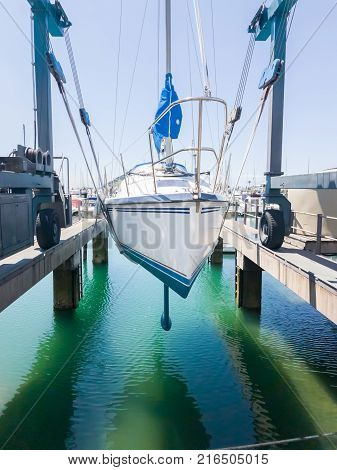 Marina hardstand travel lift with yacht hoisted for maintenance