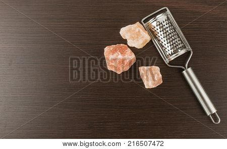 Himalayan salt with grater. Pink Himalayan salt with grinder on wooden background. Metal silver grater and red salt.