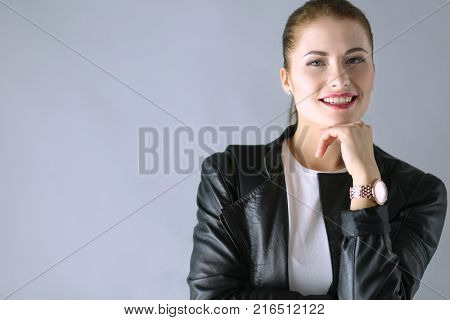 Portrait of beautiful young brunette woman in stylish black jacket on gray