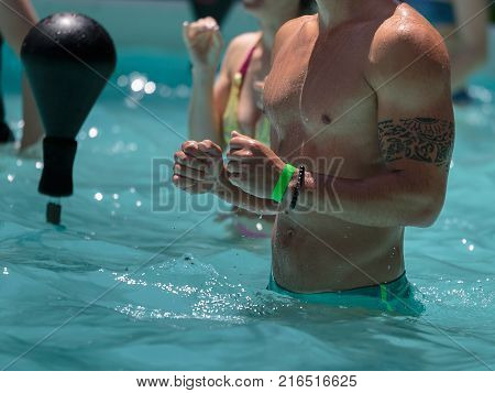 Rimini, Italy - june 2017: Boy Doing Water Aerobics with Boxing Speed Ball in an Outdoor Swimming Pool.