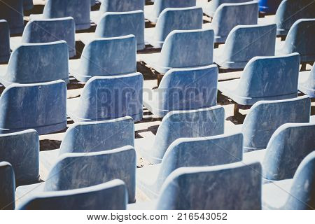Back view of blue plastic seats in an open-aitr thetre. Abstract pattern.