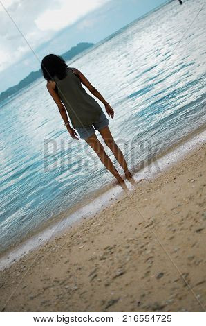 Girl on a Beach Dipping her Toes in Water