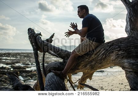 Man Sitting on a Fallen Tree or Woods on a Beach