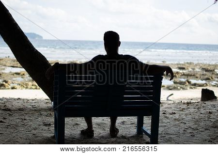 Man Sitting alone on a bench near Seashore