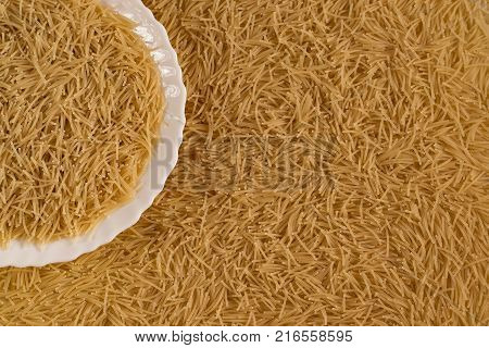 Uncooked vermicelli lying on a plate and around it close-up