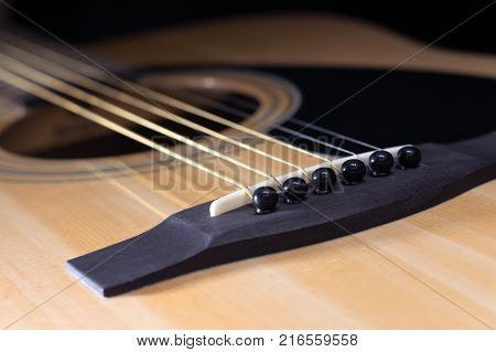 Close-up of rosette and strings of the acoustic guitar on black background
