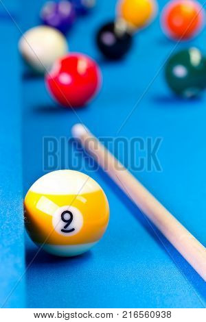 Billiard pool game nine ball with nineball balls and cue on billiard table with blue cloth selective focus on nine ball