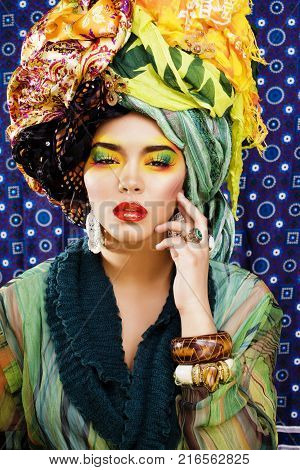 beauty bright woman with creative make up, many shawls on head like cubian, ethno look closeup colored