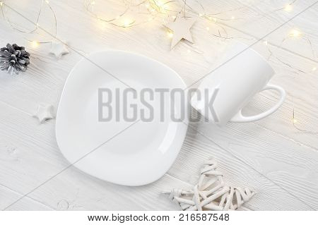 Mockup white plate and mug on a christmas white wooden background with a mest for your text, top view.