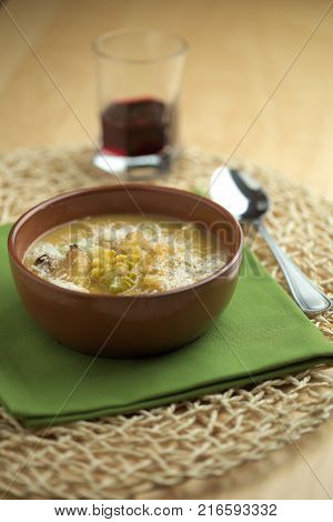 Cauliflower soup into cup, croutons of bread over tablecloth with spoon