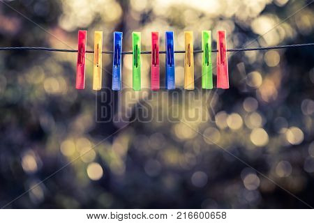 Colorful pegs hanging on clothesline. Cross processing effect applied
