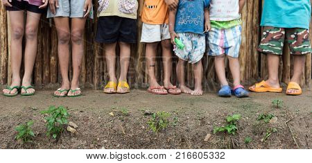 PHOP PHRATAK/THAILAND - August 22:An unidentified children stand up The back is a wooden wall.Footless shoes With damp ground. on August 222017 in PHOP PHRATAK/THAILAND.
